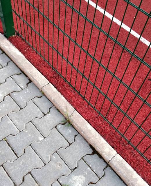 Close-up of white marking lines of outdoor basketball court fenced with protective metal fence. Zaunbau Usedom