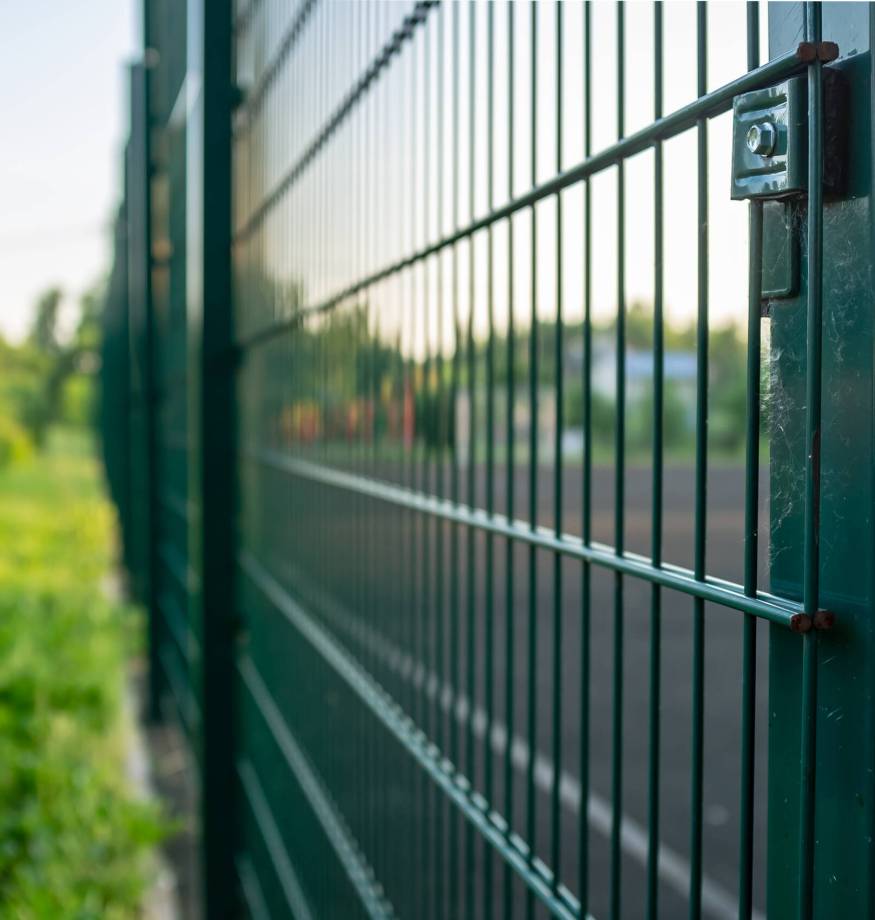 Sports ground is fenced with a green welded mesh fence, outdoors, in the evening at sunset. Zaunbau in Anklam